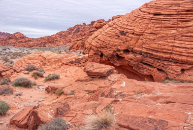 Overton, Nevada, ABD - 24 Şubat 2010: Ateş Vadisi. Kuru çöl zemininde, kalın gri bulutların altında, platodaki kırmızı kayalar çizilmiş ve çatlamış..