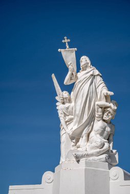 Santa Barbara, Kaliforniya, ABD - 8 Şubat 2022: Calvary Mezarlığı. Kurtarıcı İsa 'nın anıtsal heykeli ve mavi gökyüzüne karşı cezalandırıcı. Melek ve günahkar ayaklarının dibinde.