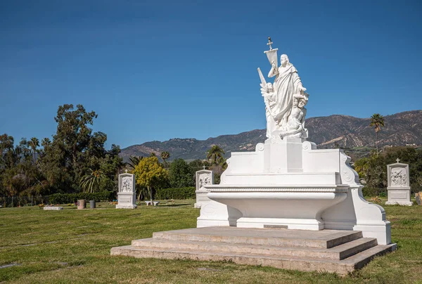 カリフォルニア州サンタバーバラ 2022年2月8日 カルバリー墓地 青い空の下で緑の埋葬の芝生の上で救世主と罰のイエスの中央の白いメインの像と風景 サンタ イエネス山 — ストック写真