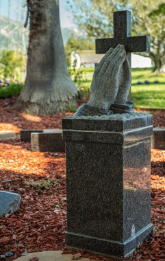 Santa Barbara, Kaliforniya, ABD - 8 Şubat 2022: Calvary Mezarlığı. Kara mermer heykel yakın çekim Palmiyeler sessizce birbirine bastırılmış haç önünde, kaide üzerinde.