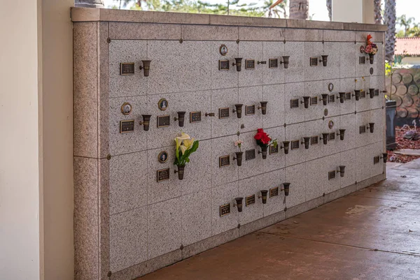 美国加利福尼亚州圣巴巴拉 2022年2月8日 加略墓地 大型灰色大理石墙的闭合壁龛 每个壁龛上都有火化骨灰骨灰 前面有花 免版税图库照片