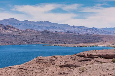 Nelson, Nevada, ABD - 21 Mayıs 2011: İkisi de mavi bulut altında mavi Colorado Nehri 'nin kuru kahverengi çöl kıyıları. Arizona tarafındaki dağlar.