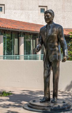 Simi Valley, California, ABD - 27 Nisan 2022: Ronald Reagan Başkanlık Kütüphanesi. Kütüphanesinin girişinde Lifesize bronz heykelinin yakın çekimi. Arkada beyazlatılmış beyaz duvarlar var. Biraz yeşil yaprak..