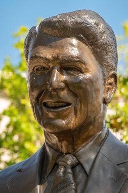 Simi Valley, California, ABD - 27 Nisan 2022: Ronald Reagan Başkanlık Kütüphanesi. Kütüphanesinin girişinde Lifesize bronz heykelinin kravatıyla yüz resmi. Biraz yeşil yaprak..