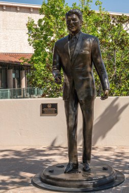 Simi Valley, California, ABD - 27 Nisan 2022: Ronald Reagan Başkanlık Kütüphanesi. Kütüphanesinin girişinde Lifesize bronz heykelinin ön tarafında. Arkada beyazlatılmış beyaz duvarlar var. Biraz yeşil yaprak..