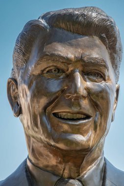 Simi Valley, California, ABD - 27 Nisan 2022: Ronald Reagan Başkanlık Kütüphanesi. Mavi gökyüzüne karşı kütüphanesinin girişinde Lifesize bronz heykeli ile yüz portresi.
