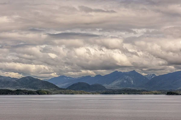 太平洋岸線 アラスカ州 2011年7月16日 カナダ太平洋の薄緑色の平らな水の後ろの厚い緑の森の丘陵海岸線に沿って重い白と灰色の雲の下でロッキー背の高い山々 — ストック写真