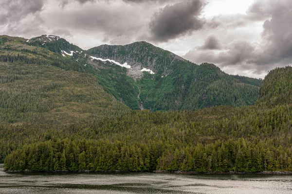 太平洋岸線 アラスカ州 2011年7月16日 激しい雲の下でのカナダのロッキー山脈 詳細は 濃い森の緑の側面に泥だらけの滝や雪のパッチを示しています — ストック写真