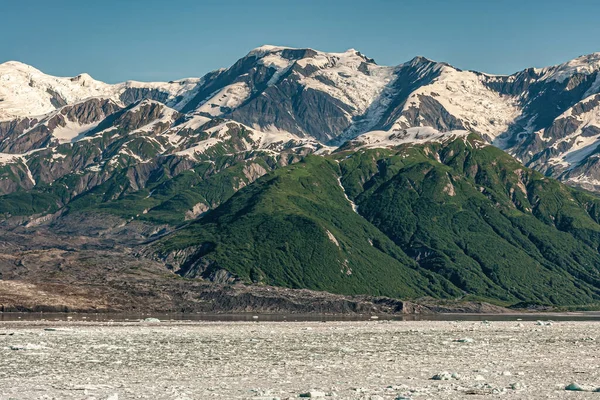 2011年7月21日 一部の森林に覆われた山脈の前に浮かぶ氷の破片が青い空の下で雪の上に浮かんでいる風景 — ストック写真
