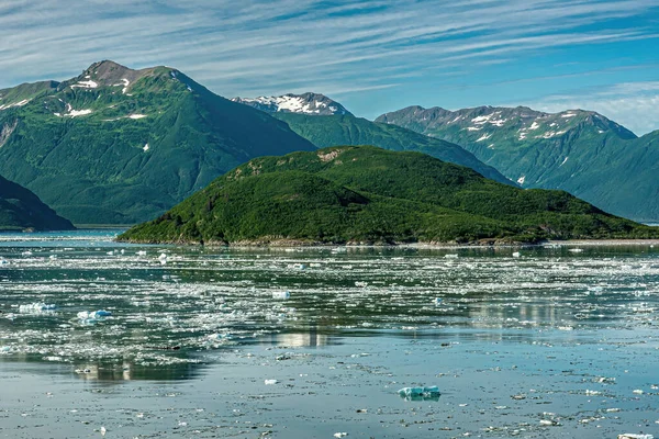 2011年7月21日 青い雲の下の緑の森の島の前の青い海の水に浮かぶ氷 地平線上の雪の山の範囲 — ストック写真