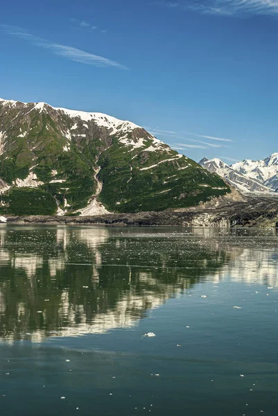 2011年7月21日 美国阿拉斯加州的幻灭湾 与特纳冰川相邻的绿山侧翼在蓝天下映衬蓝海水 后背有雪山的肖像 — 图库照片