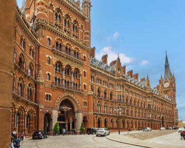 London, Great Britain - July 3, 2022: Red brick historic St. Pancras Renaissance Hotel under blue sky with cars up front.