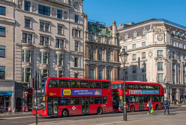 London, UK- July 4, 2022: Trafalgar Square. Double decker red buses on Cockspur street and Spring Gardens intersection. People and historic building architecture.