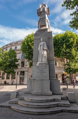 London, UK- July 4, 2022: Off Trafalgar Square. Edith Cavell Memorial is tall stone obelisk with Marble statues featuring her image and appealing humanity on St. Martin Place under blue sky.