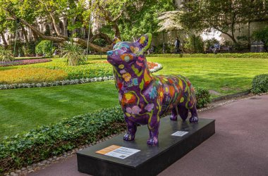 London, UK - July 4, 2022: Whitehall Gardens. Dog statue called Emma by Rebecca Hardaker is colorful appearance with green lawn in back and tree foliage above.
