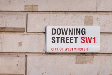 London, UK - July 4, 2022: Along Whitehall A3212, Closeup of Downing Street SW1, black and red official street sign against beige wall.