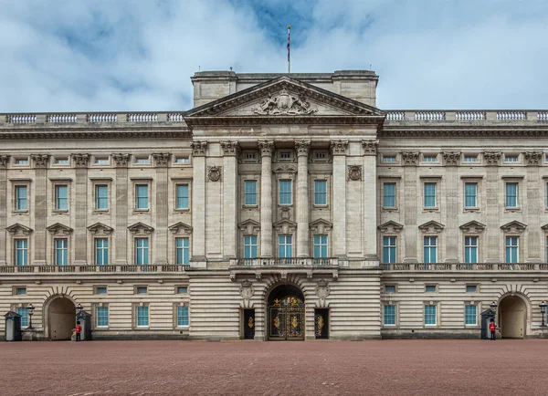 London, England, UK - July 6, 2022: Buckingham Palace beige stone building from one Queen's Guard to another under blue cloudscape. Columned central part kept in center.
