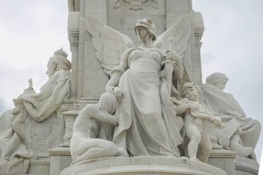London, England, UK - July 6, 2022: Victoria Memorial. Closeup of white marble Justice statue combination. Queen left, and motherhood on the right. Gray sky.