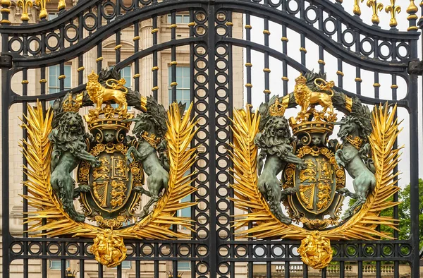 London, England, UK - July 6, 2022: Buckingham Palace. Closeup of two identical golden royal coat of arms fixed to black metal main gate.