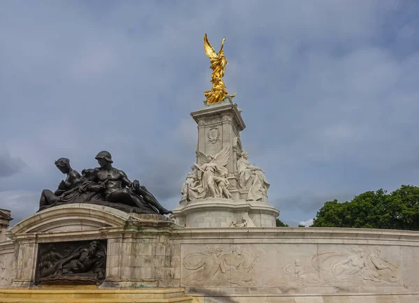London, England, UK - July 6, 2022: Victoria Memorial. Combination shot of fountain couple statue with adjacent mural in front of Queen, Truth, and Winged Victory under blue sky.