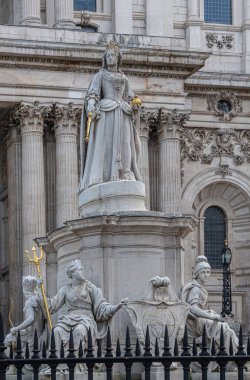 London, England, UK - July 6, 2022: St. Paul's Cathedral. Closeup, Statue of Queen Anne on West churchyard. Gray marble with golden details. Columned facade as backdrop.