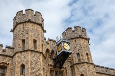 London, England, UK - July 6, 2022: Tower of London. Clock between 2 brown-beige stone lookout towers at center of Waterloo Block building under blue cloudscape