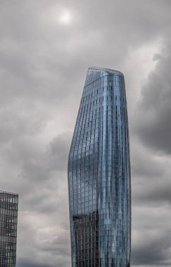London, England, UK - July 6, 2022: From Thames River. Closeup of top half of blueish One Blackfriars skyscraper against dark gray sky.