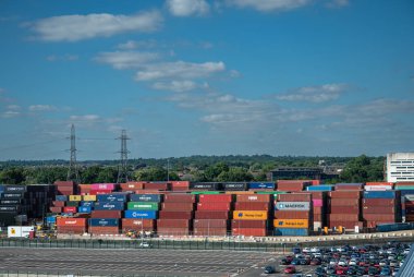 Southampton, İngiltere - 7 Temmuz 2022 Liman manzarası. Tüm kaynakların istiflenmiş konteynırlarıyla dolu rıhtım. Mavi bulutların ve yeşil kuşağın altında araba park ediyor..