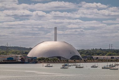 Southampton, İngiltere - 7 Temmuz 2022 Liman manzarası. Veolia Çevre Hizmetleri, kasabanın karşısındaki nehir test kıyı şeridinde mavi bulutların altında bulunan küresel bir bina. Önde küçük yatlar var.