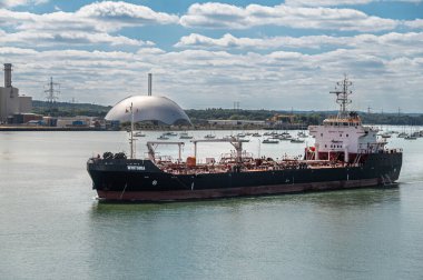 Southampton, İngiltere - 7 Temmuz 2022 Liman manzarası. Whitonia siyah-kırmızı küçük yakıt tankeri mavi bulutlar altında limana yanaşıyor. Arka tarafta kubbe şeklinde Veolia Çevre Hizmetleri binası var.