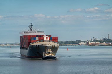 Southampton, İngiltere - 7 Temmuz 2022 Liman manzarası. Svitzer Bargate römorkörü Independent Horizon konteynır gemisini limana çekti mavi gökyüzünün altındaki mavi nehir suyu üzerinde.