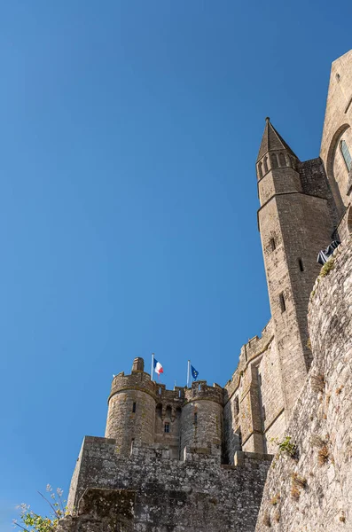 2022年7月8日フランス ノルマンディーのモンサンミシェル 青い空に対して上にフランスとヨーロッパの旗を特徴とする茶色の石造りの城と教会の壁の詳細 — ストック写真
