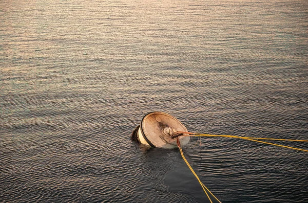 St. Malo, Brittany, France - July 8, 2022: Closeup, Sunrise on buoy moored in Rance River mouth waters. Yellow cables lead away.