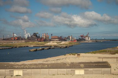 Avrupa, Fransa, Dunkerque - 9 Temmuz 2022: Liman manzarası. Enerji rıhtımındaki kömür terminalinde kırmızı vinçler ve mavi bulutların altında elektrik santrali var. Kuzey Denizi 'ne bakan limanda görüldü.
