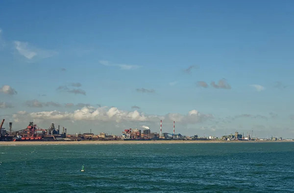 Europe, France, Dunkerque - July 9, 2022: Wide landscape from North Sea along Route du Bassin Maritime leading in Quai de Grande Synthe. Power generation, grain silos, container terminal