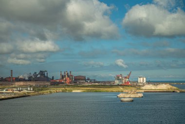 Avrupa, Fransa, Dunkerque - 9 Temmuz 2022: Liman manzarası. Kömür santraline ve mavi bulutların altındaki depo rıhtımına bakıyor.