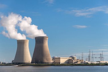 Antwerpen, Flanders, Belçika - 10 Temmuz 2022: Peyzaj, Soğutma kuleleri akşam mavi havada buhar üfleme ve Scheldt Nehri 'nden görülen Doel Nükleer Santrali binaları