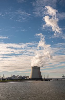 Antwerpen, Flanders, Belçika - 10 Temmuz 2022: Portre, Serinletici Kuleler Üzerinde Günbatımı ve Mavi Bulutlar 'a buhar üfleyen Doel Nükleer Santrali. Ufukta Europa konteyner terminali