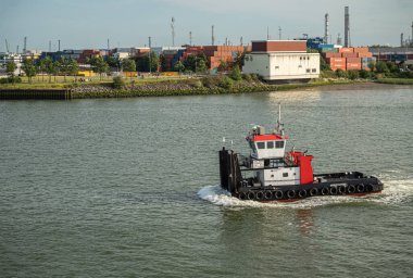 Rotterdam, Hollanda - 11 Temmuz 2022: Kırmızı-beyaz-siyah Anna Marie römorkörünün yaklaşması 2. Petroleumhaven 'dan New Meuse Nehri' ne. Yığılmış konteynır ve bacaların arkaplanı
