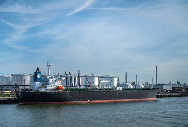 荷兰鹿特丹 2022年7月11日 Kriti Rock号油轮在蓝色云彩外壳炼油厂烟囱下的石油和天然气储气罐前的码头进行加工 — 图库照片