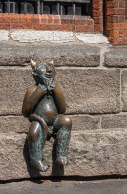 Almanya, Lubeck - 13 Temmuz 2022: Marienkirche 'in güney tarafında, Mary' nin kilisesi. Şeytanın taşında oturan gülümseyen şeytanı temsil eden küçük bronz bir heykel. Yerel mitoloji