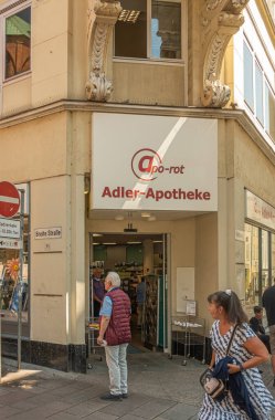 Almanya, Lubeck - 13 Temmuz 2022: Breite ve Fleischhauer caddelerinin köşesindeki Adler Eczanesi 'nin girişi. Bej arka planda kırmızı isim. Yayalar hazır.