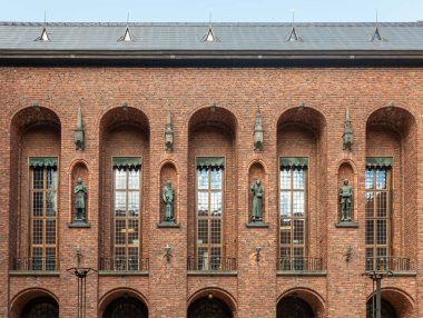 İsveç, Stockholm - 16 Temmuz 2022 Belediye veya Stadshuset. 4 bronz heykel, yüksek ince pencereler arasında, avlunun güney cephesindeki tuğlalarda duruyor.