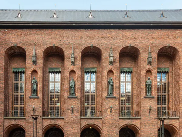 İsveç, Stockholm - 16 Temmuz 2022 Belediye veya Stadshuset. 4 bronz heykel, yüksek ince pencereler arasında, avlunun güney cephesindeki tuğlalarda duruyor.