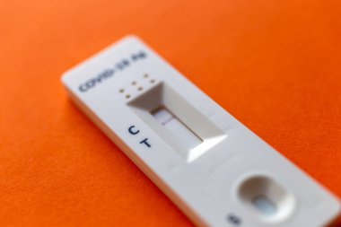 Turuncu bir arkaplanda COVID-19 için hızlı test aygıtı kullanarak negatif test sonucu.