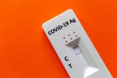 Turuncu bir arkaplanda COVID-19 için hızlı test aygıtı kullanarak negatif test sonucu.