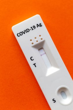 Turuncu bir arkaplanda COVID-19 için hızlı test aygıtı kullanarak negatif test sonucu.