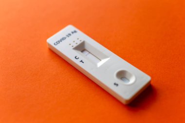 Turuncu bir arkaplanda COVID-19 için hızlı test aygıtı kullanarak negatif test sonucu.