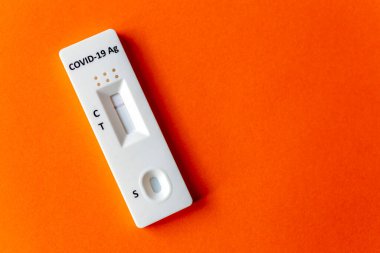 Turuncu bir arkaplanda COVID-19 için hızlı test aygıtı kullanarak negatif test sonucu.