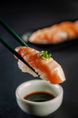 Blowtorcherd salmon onigiri on chopsticks with salmon onigiri varieties on a background.